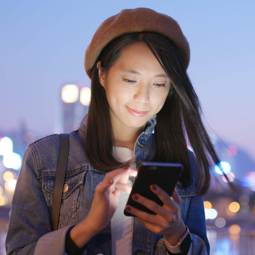 A woman using an electronic device outdoors, benefiting from our Neighborhood roaming (SmartTown Wi-Fi).